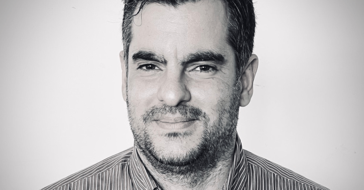 A black and white headshot of a male who is smiling