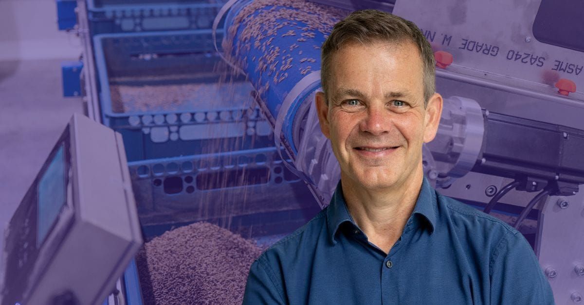 Man posing in front of a factory machine
