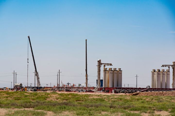 Active Permian Basin oilfield services operation — frac spread with crane and sand storage silos