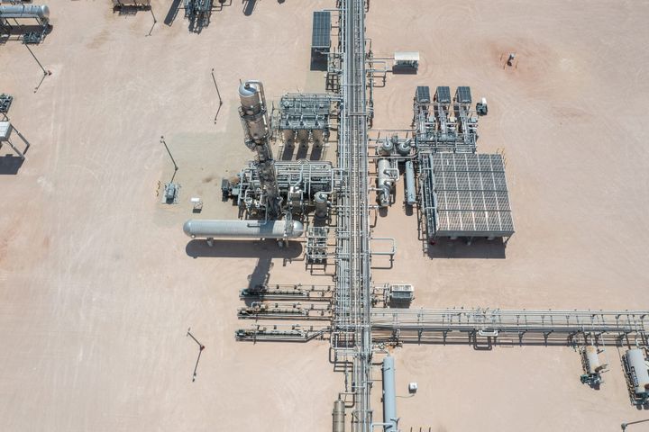 Aerial view of gas processing facility with four storage tanks and solar panels