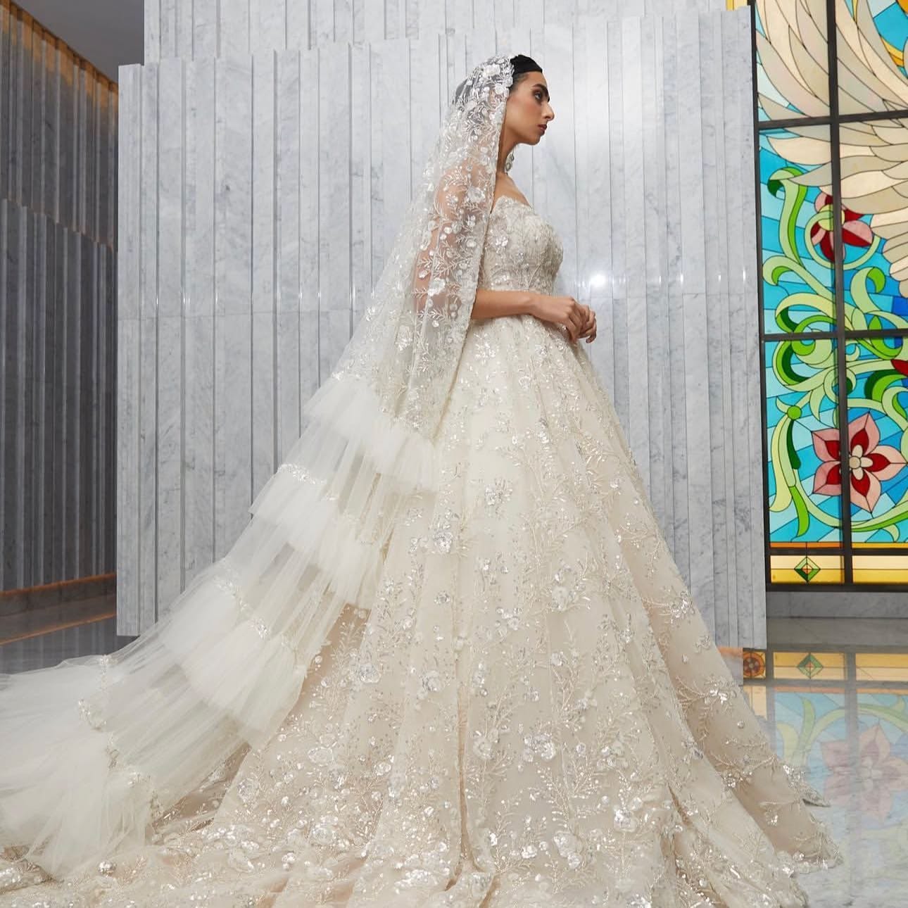 AlAjlan’s Bridal Collection is particularly celebrated for its ethereal elegance, featuring intricately embroidered gowns with delicate lacework, beading, and flowing silhouettes that embody romance and grandeur.