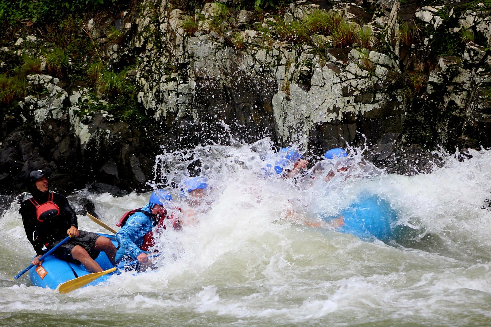 Full commitment — the raft disappears under a wall of whitewater as the rapid hits hard and fast.