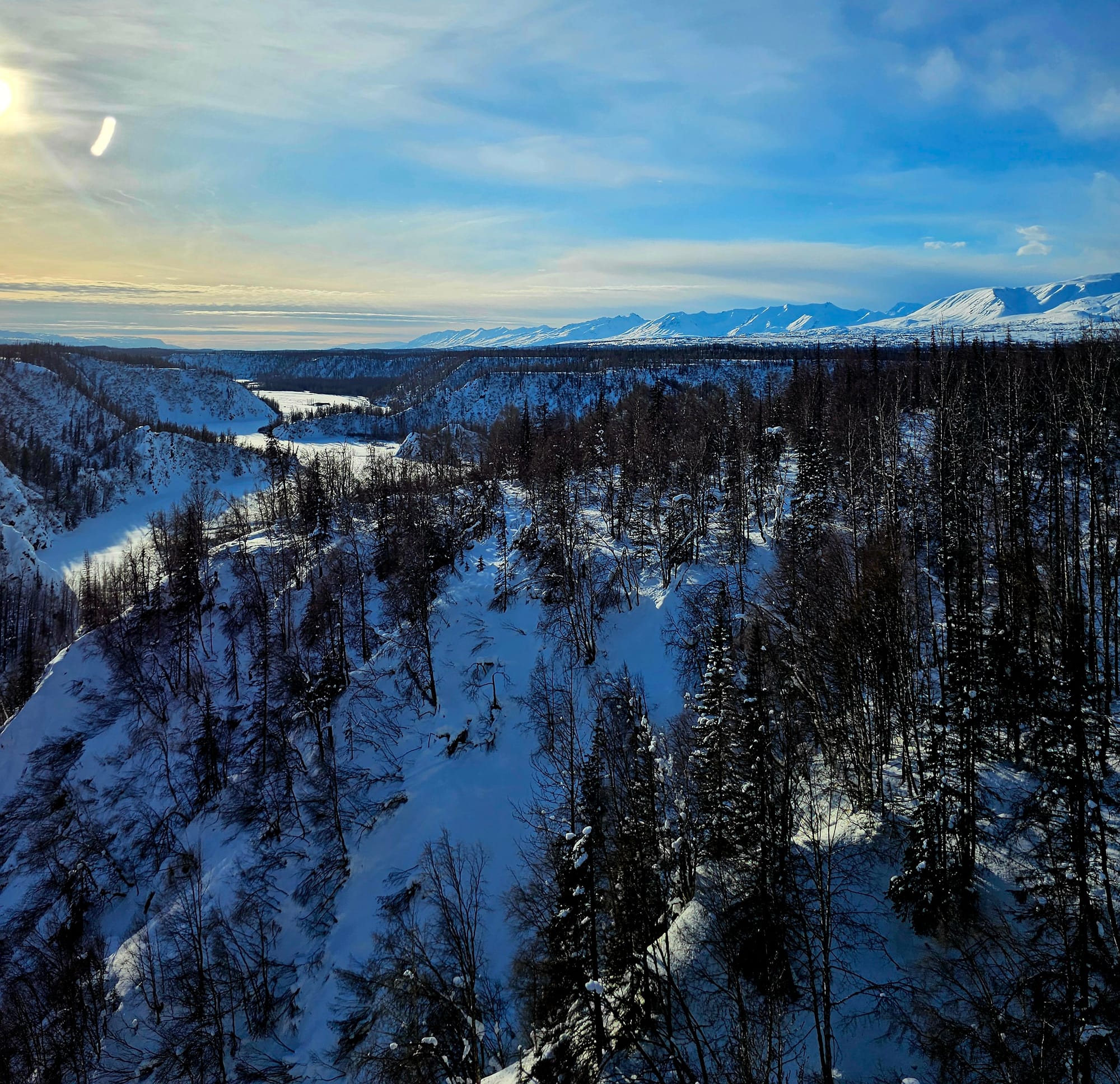 Rugged Interior Alaska from the Aurora Winter Train — frozen river valleys, dense black spruce and wide, unbroken ridgelines stretching far beyond the road system.