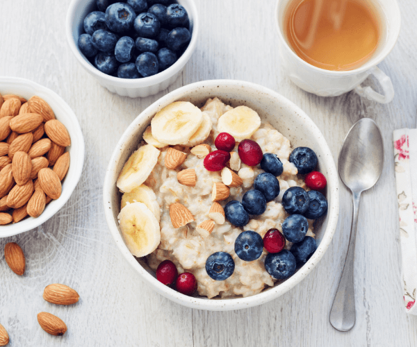 Oatmeal porridge with berries, nuts and cup of green tea