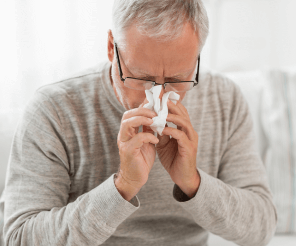 Senior man blowing nose