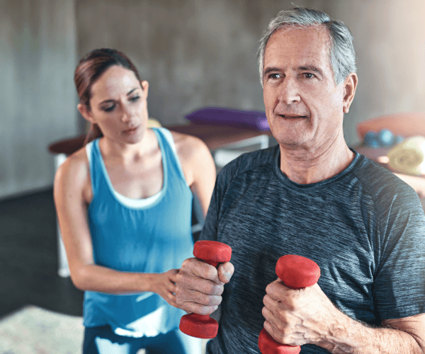 Older man with trainer using hand weights
