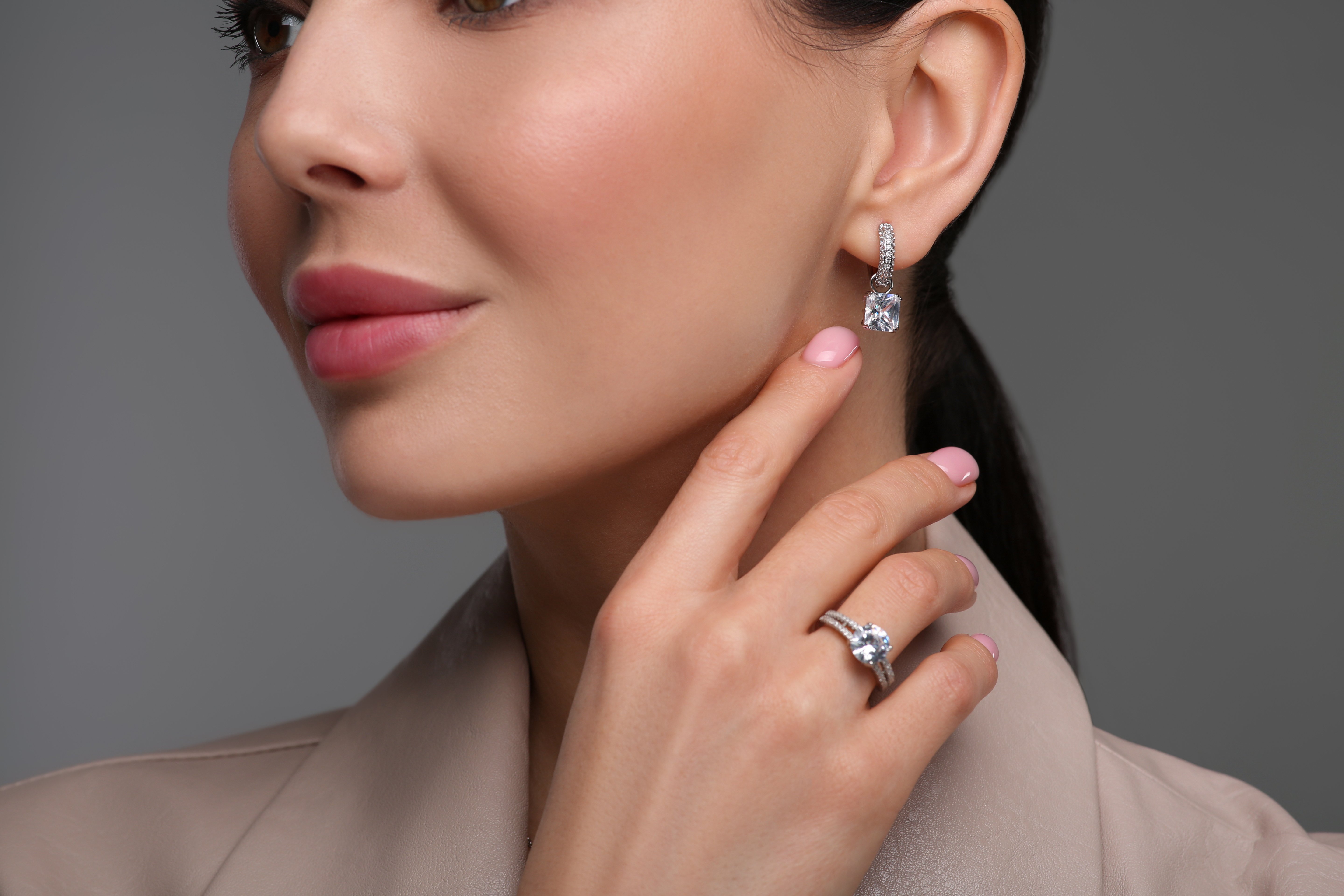 Young woman with elegant jewelry on dark grey background, closeup