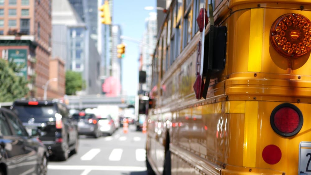 Yellow school bus stopped in city traffic during weekday commute