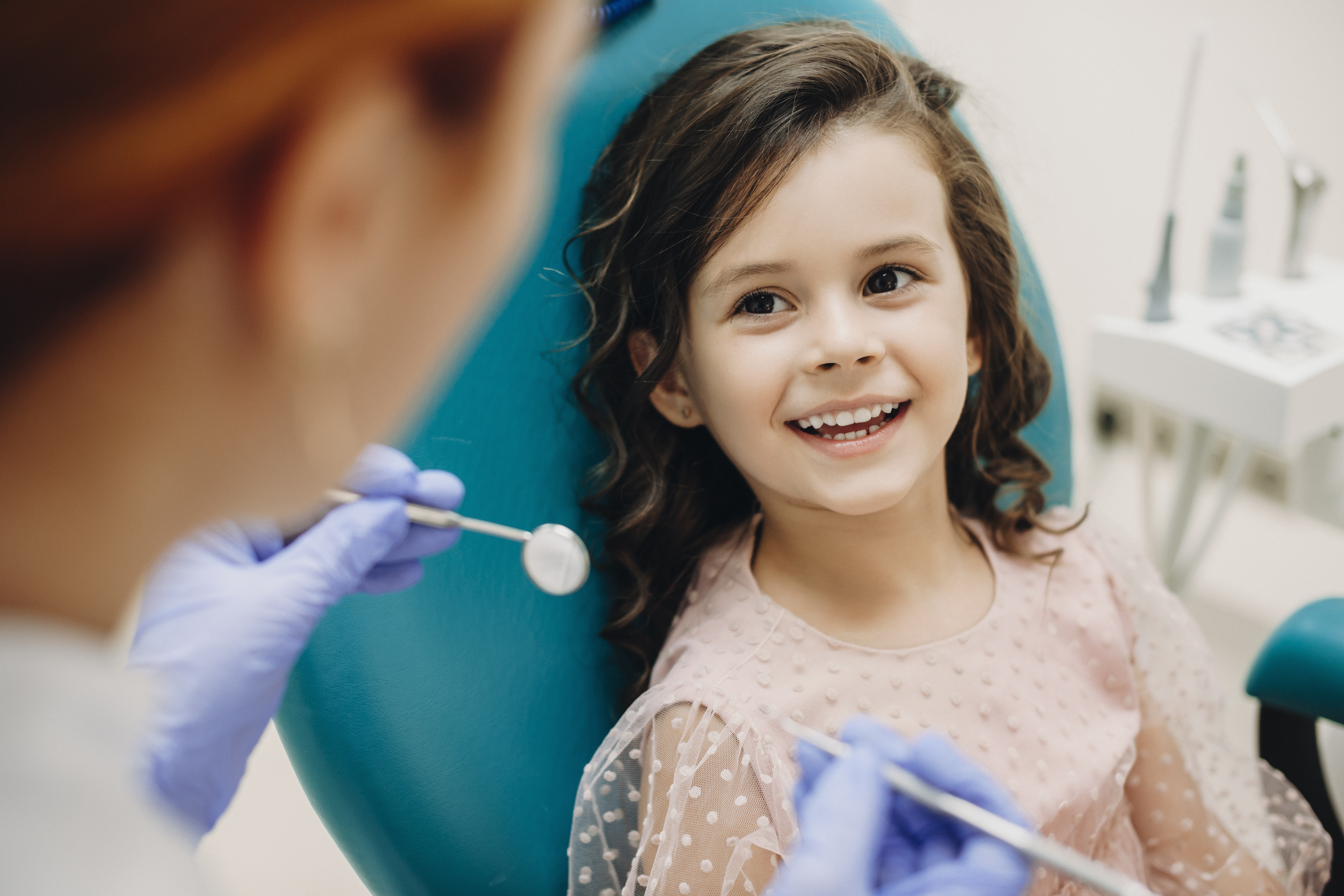Lovely little kid smiling while talking with the pediatric dentist after doing a tenth examination in a pediatric stomatology.