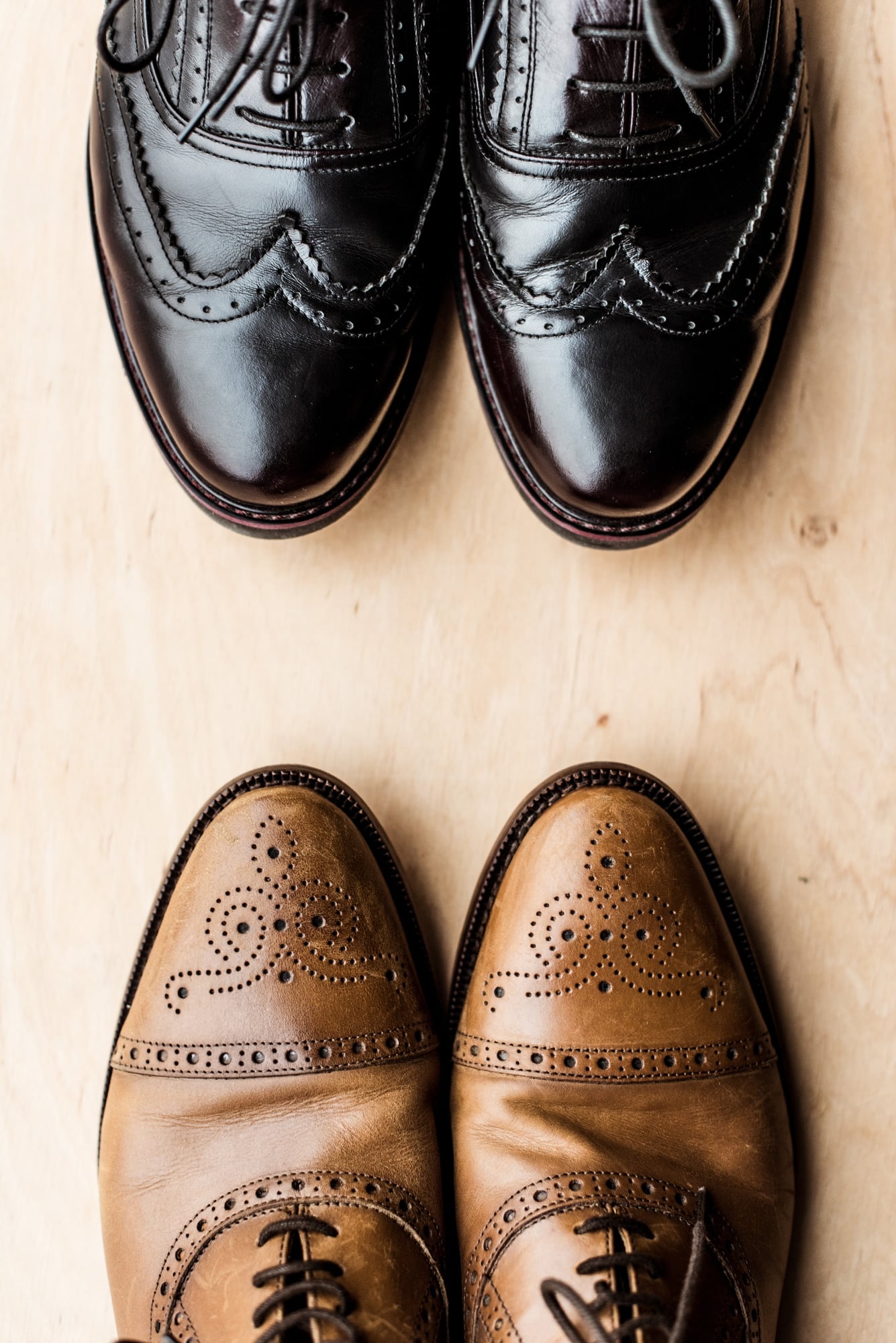Top view of black and brown pairs of leather shoes on wooden floor 