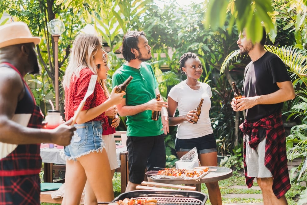 Group of diverse people having barbecue/barbeque party at home, cooking grilled meat/beef for lunch, happy friends party lifestyle concept