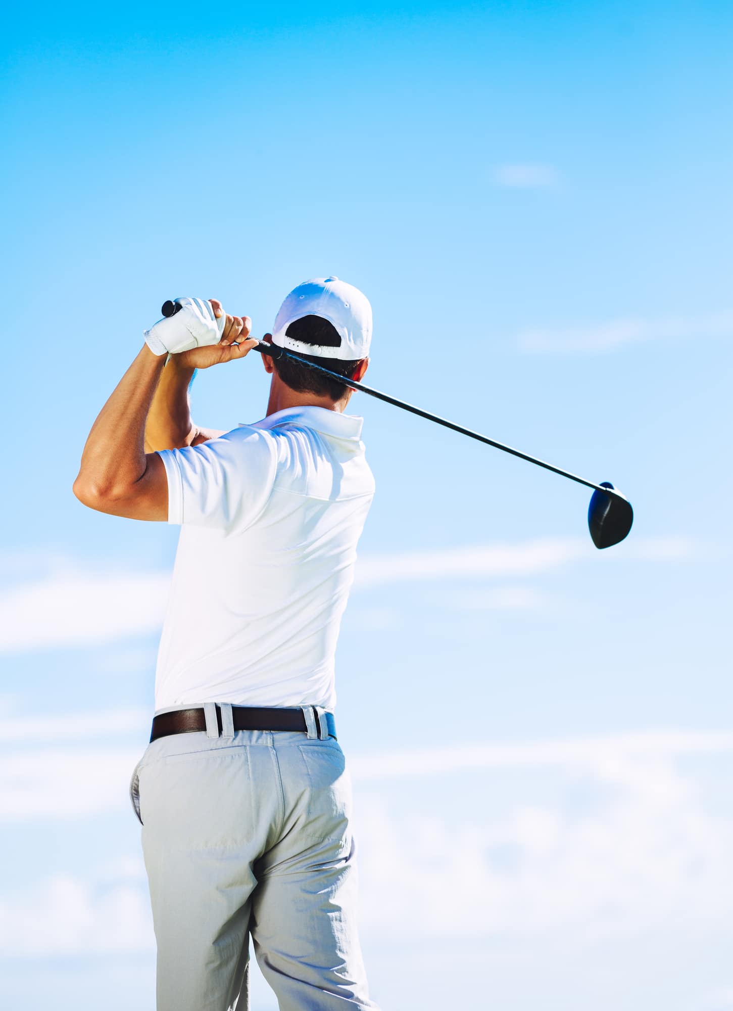 Man Swinging Golf Club with Blue Sky Background
