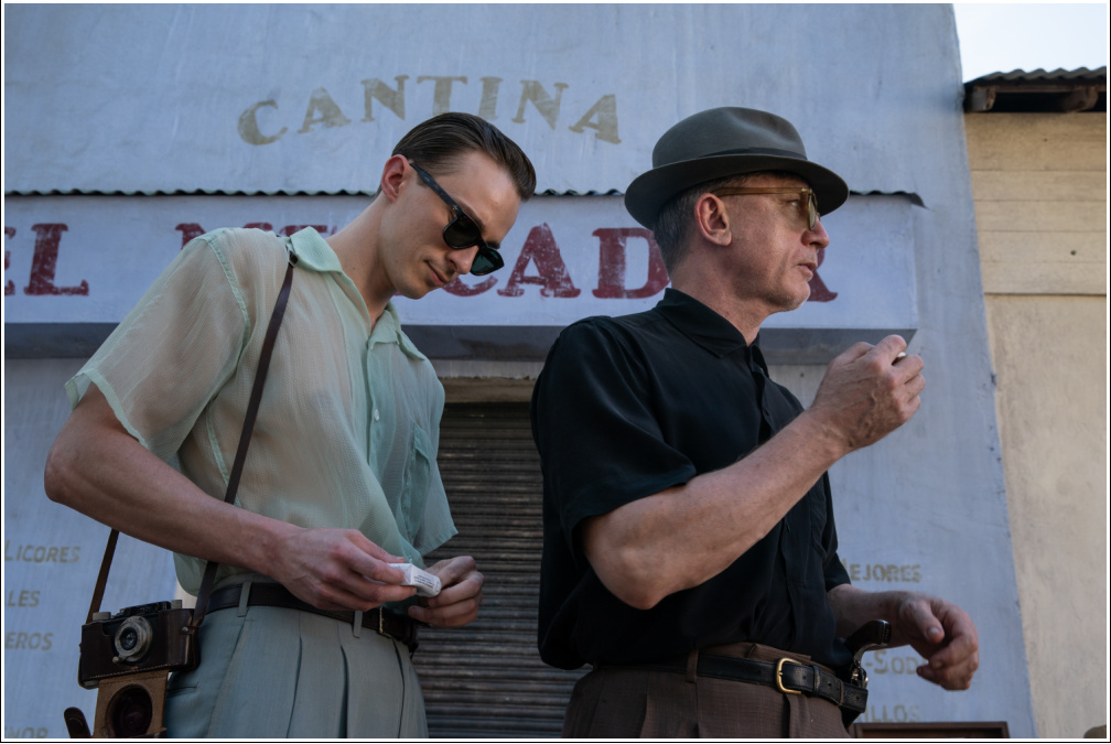 Drew Starkey and Daniel Craig stand outside a cantina in 1950s attire, both holding cigarettes.