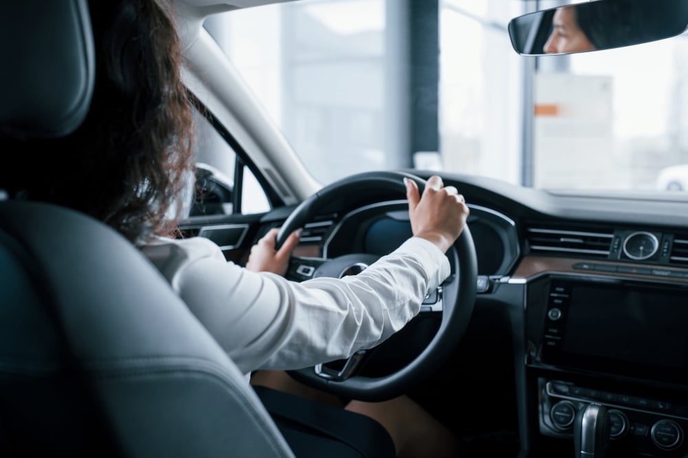 Hands on steering wheel. beautiful businesswoman trying her new car in the automobile salon
