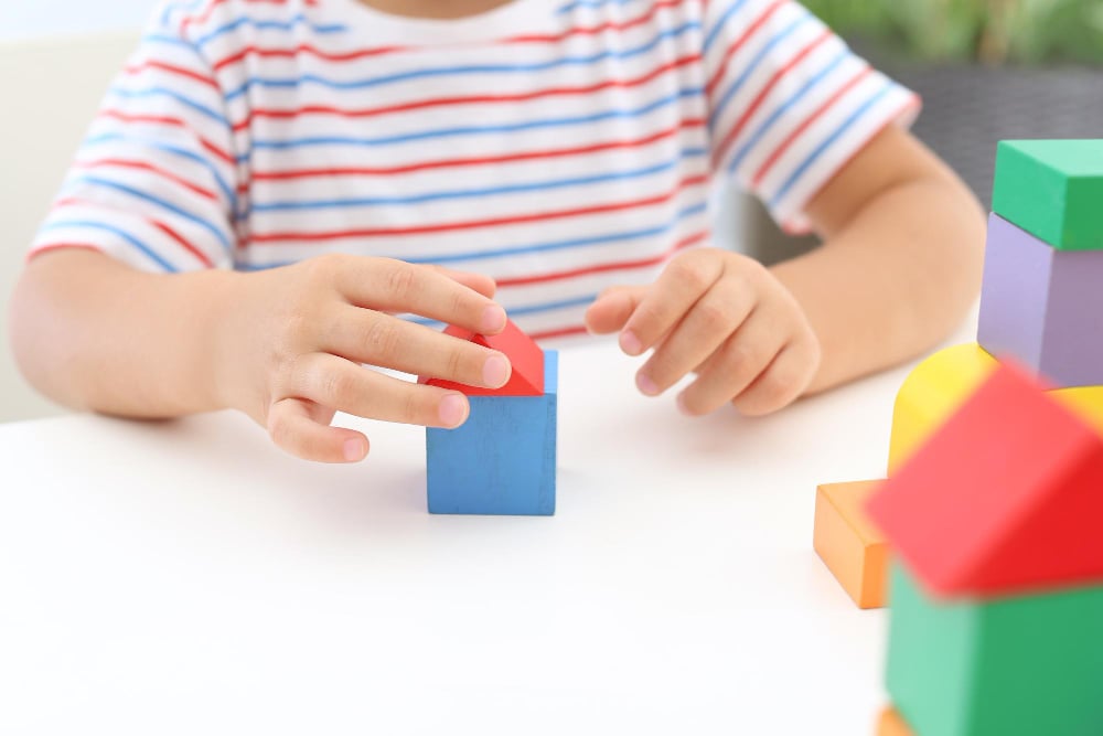 Photo little boy playing with colorful blocks at white table closeup educational toy
