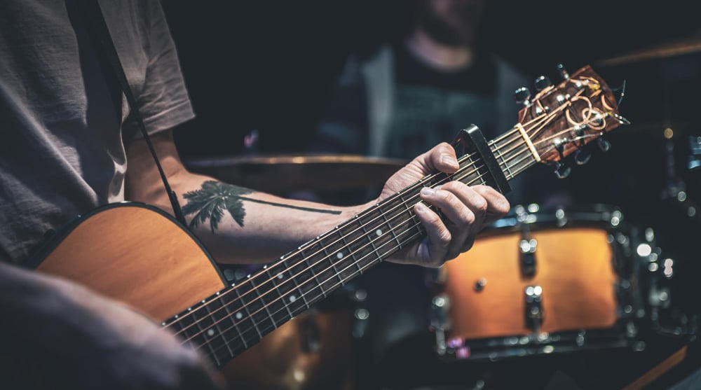 A man plays an acoustic guitar in the dark closeup
