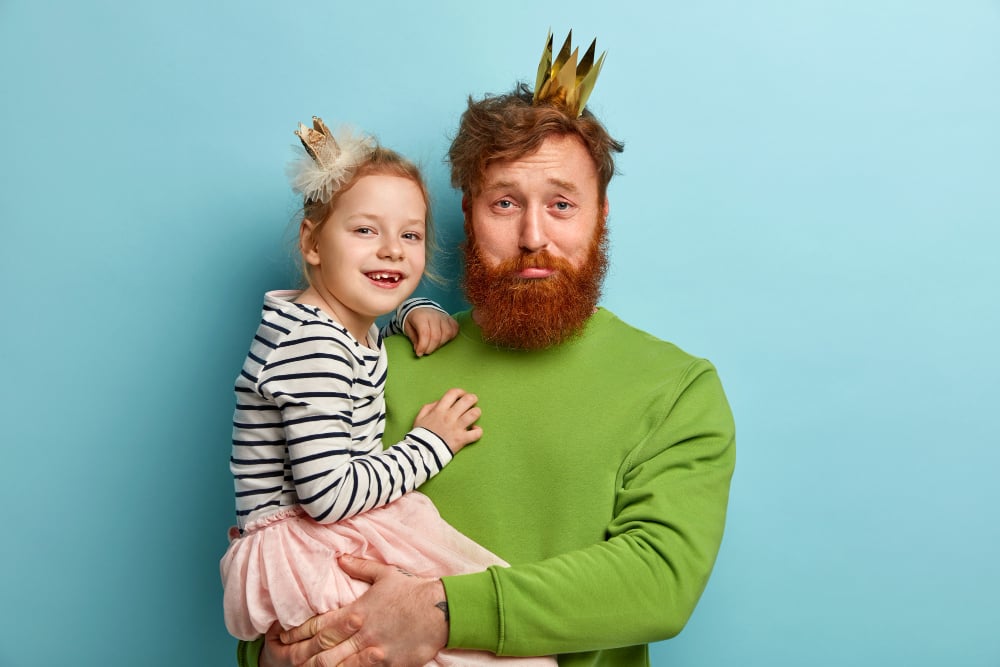 Free photo man with ginger beard and his daughter with party accessories

