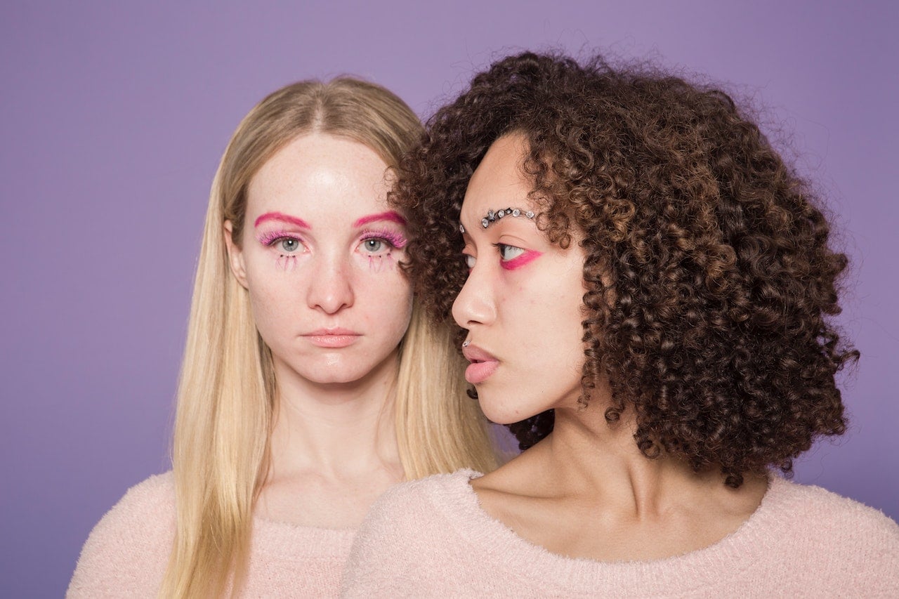 Emotionless multiethnic women with colorful makeup in studio
