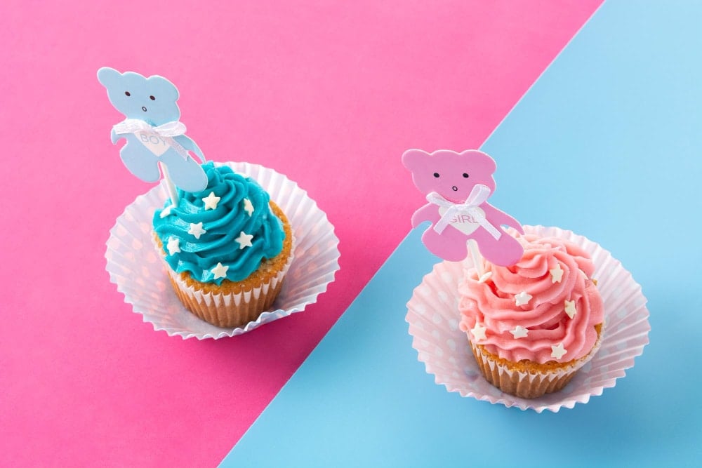 Pink and blue cupcakes for baby shower on pink and blue background
