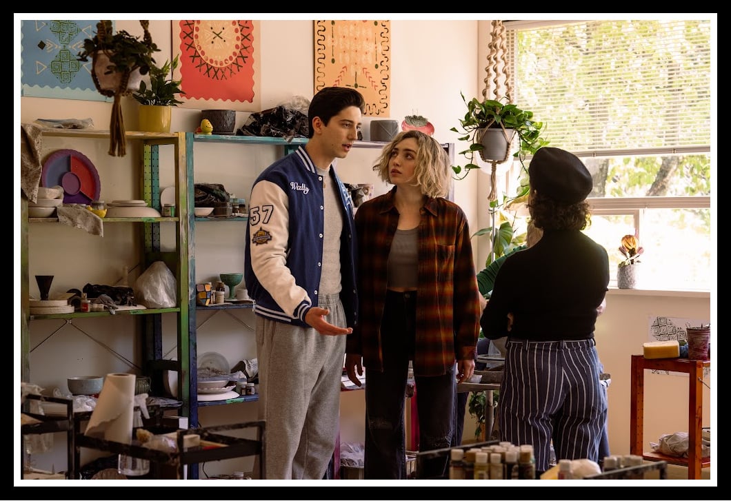 Wally Clark (Milo Manheim) and Maddie Nears (Peyton List) engage in a serious conversation in a brightly lit classroom filled with art supplies in School Spirits Season 2.