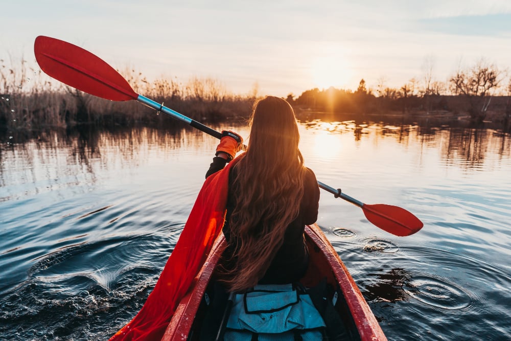 Woman holding paddle in a kayak on the river

