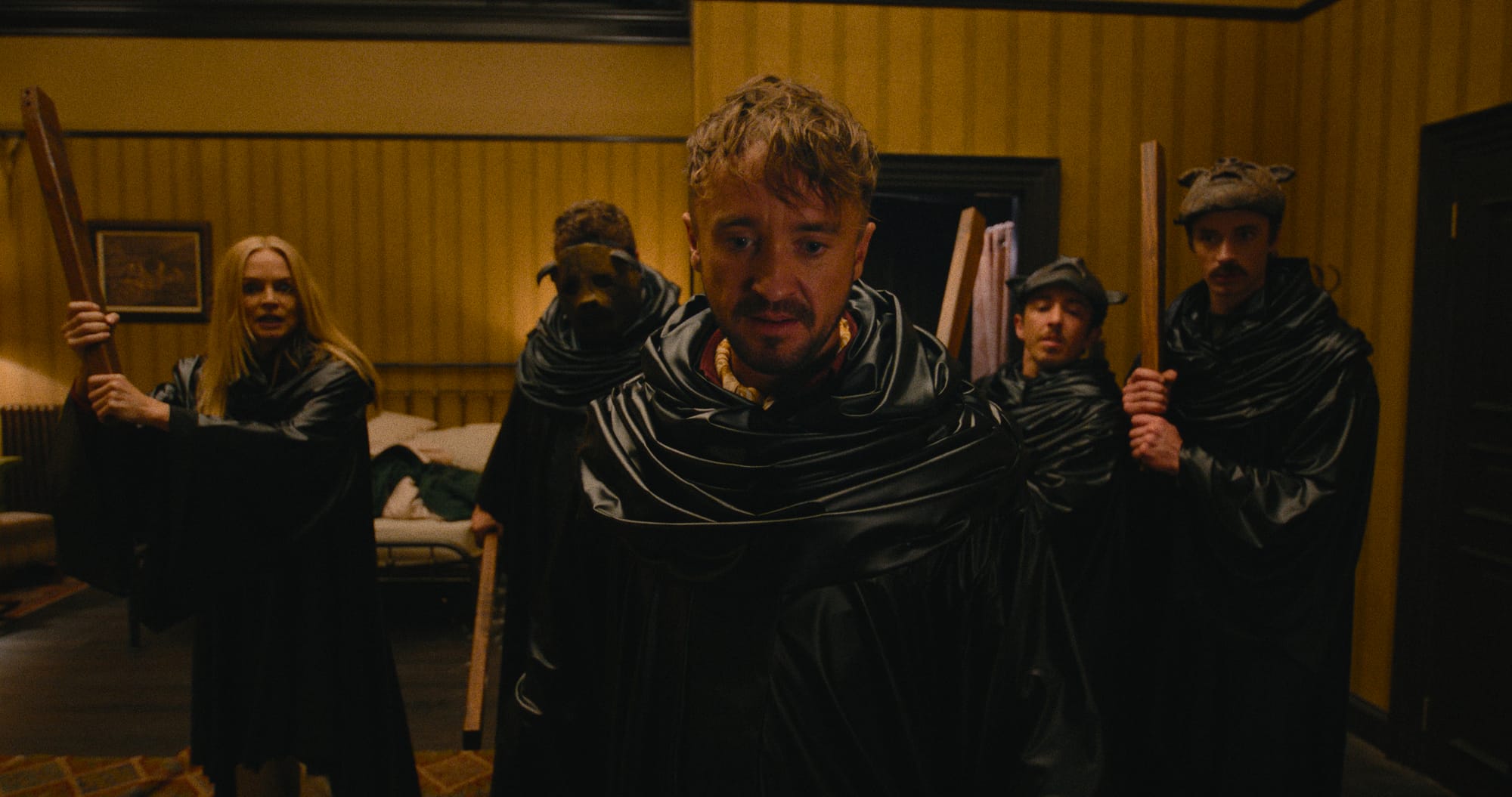 Tom Felton as Kevin stands surrounded by cloaked figures including Heather Graham as Sharon in a tense scene from They Will Kill You (2026), Warner Bros. horror thriller.  Shorter Alt Option (if you want tighter SEO formatting):