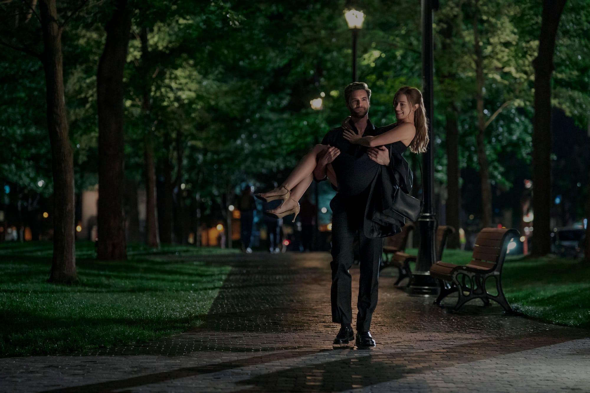 Adam carries Olive through a park at night in The Love Hypothesis.