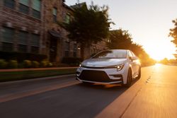 2026 Toyota Corolla Cross XLE AWD driving on city road during sunset exterior view