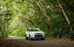 2026 Toyota Grand Highlander Hybrid MAX Platinum driving on a wooded road exterior view
