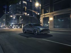 2026 Toyota Crown Nightshade driving through a downtown city street at night with LED headlights and matte-black wheels