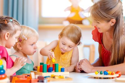 Group of children and teacher playing practical games in kindergarten