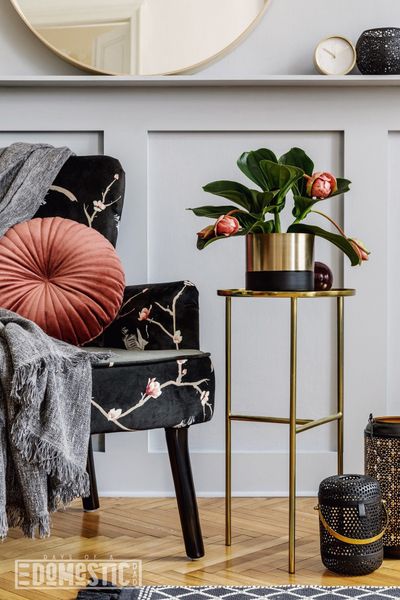 Modern concept of home staging with design armchair, round mirror, gold coffee table, pillow, plaid, lanterns, shlef, grey wa