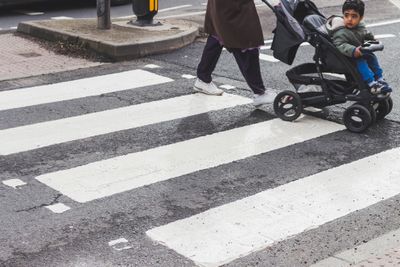 A child in a stroller crossing a zebra crossing in the city. Urban street scene focusing on pedestrian safety.