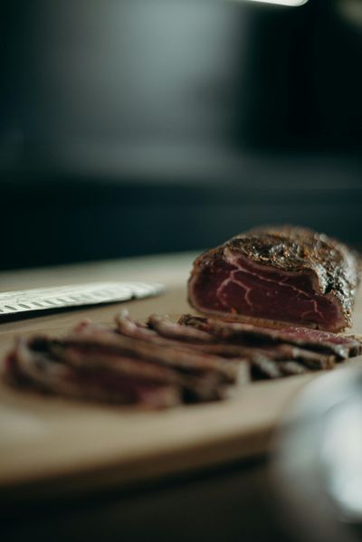 A close-up view of sliced red meat on a wooden cutting board, ideal for culinary and food-related needs.