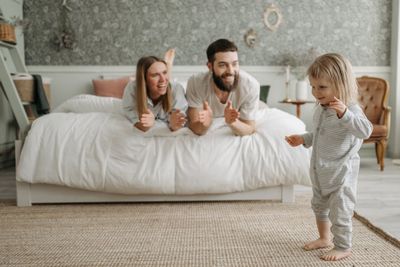 A Couple Lying on the Bed while Looking at Their Daughter Standing
