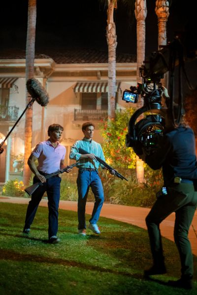 Behind-the-scenes image from Monsters_ The Lyle and Erik Menendez Story, showing two characters with rifles, along with the f