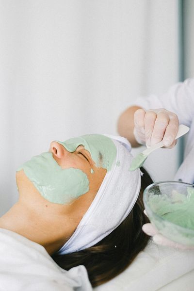 Cosmetician applying facial mask on client face