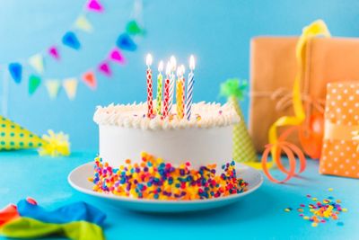 decorative-cake-with-burning-candle-blue-background