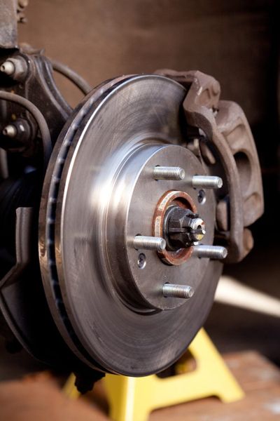 Close up shot of a newly replaced brake rotor and pads for a modern car