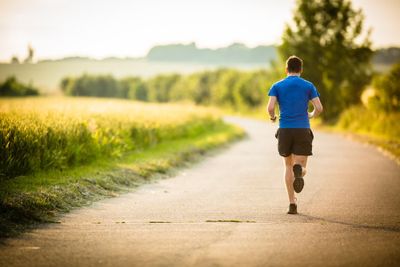 Male athlete/runner running on road - jog workout well-being concept