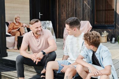 Father and Kids Sitting on Wooden Steps while Having Conversation