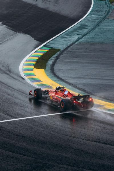 Ferrari Formula 1 car navigating a wet curve at Interlagos race track in Brazil.