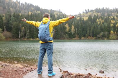 Photo happy man spreads hands to sides enjoying wild nature while hiking tourist with backpack stands