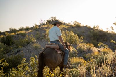Guest horseback riding through the desert landscape at a Tubac, Arizona dude ranch during golden hour