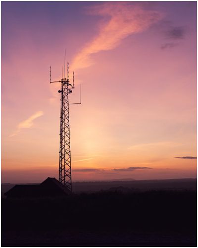 Cell tower standing tall against a colorful sunset sky, illustrating the opportunity to lease your land for cell towers and g