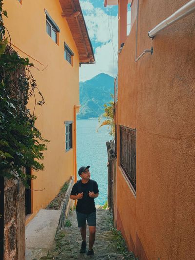 Man in Black T-shirt Standing Beside Brown Concrete Building