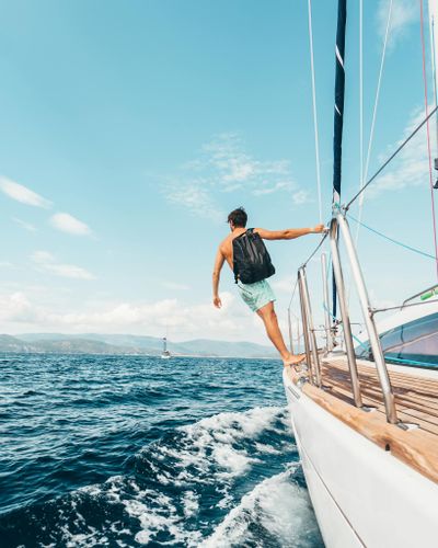 Man sailing in vibrant Greek waters, depicting freedom and adventure under clear skies.