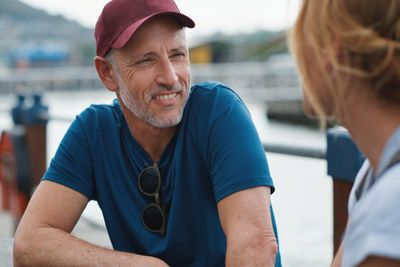 Man woman and harbor with happy conversation on travel vacation or date by ocean in summer sunshine senior couple talk and li