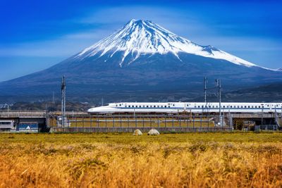 Shinkansen bullet train passing in front of snow-capped Mount Fuji in Japan