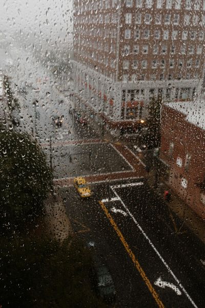 Rainy view of Greensboro NC through droplets on a window, showcasing urban atmosphere.